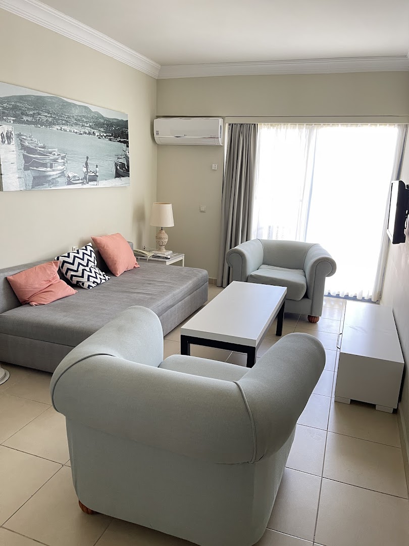 Paloma Marina Suites viesnīcas dzīvojamā zona ar dīvānu, atpūtas krēsliem un izeju uz balkonu Kušadasi