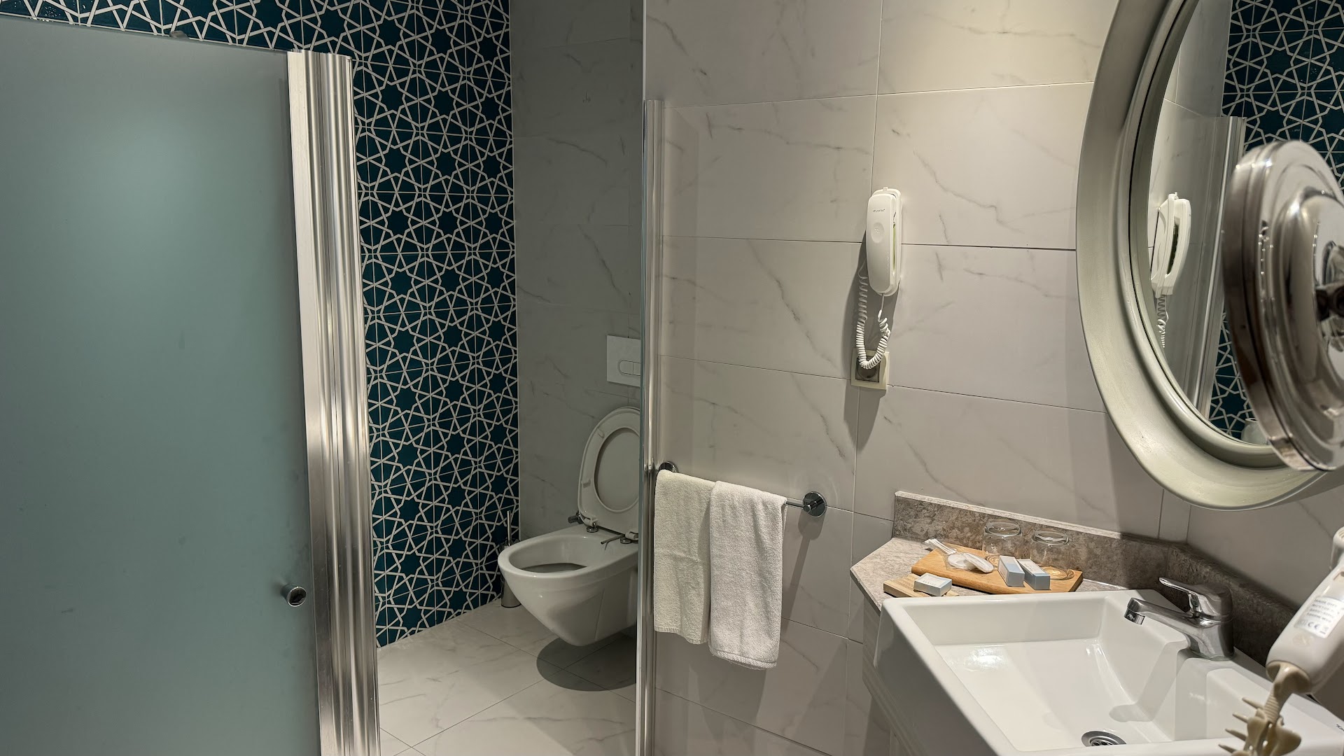 Paloma Marina Suites viesnīcas numura vannas istaba ar modernu izlietni, spoguli un dušas zonu — gaišas flīzes un dekoratīvi sienas elementi