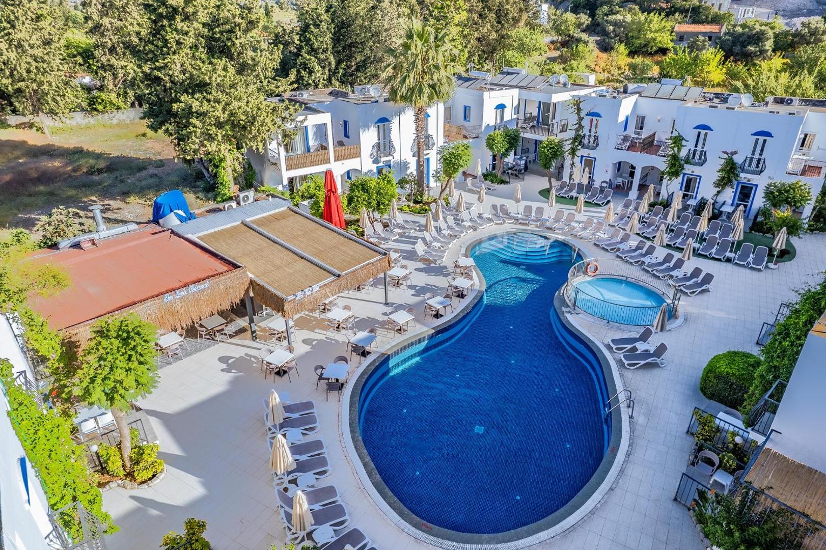 Aerofoto skats uz Paloma Marina Suites baseinu, bērnu baseinu un āra terases restorānu, ko ieskauj balti viesnīcas numuru korpusi.