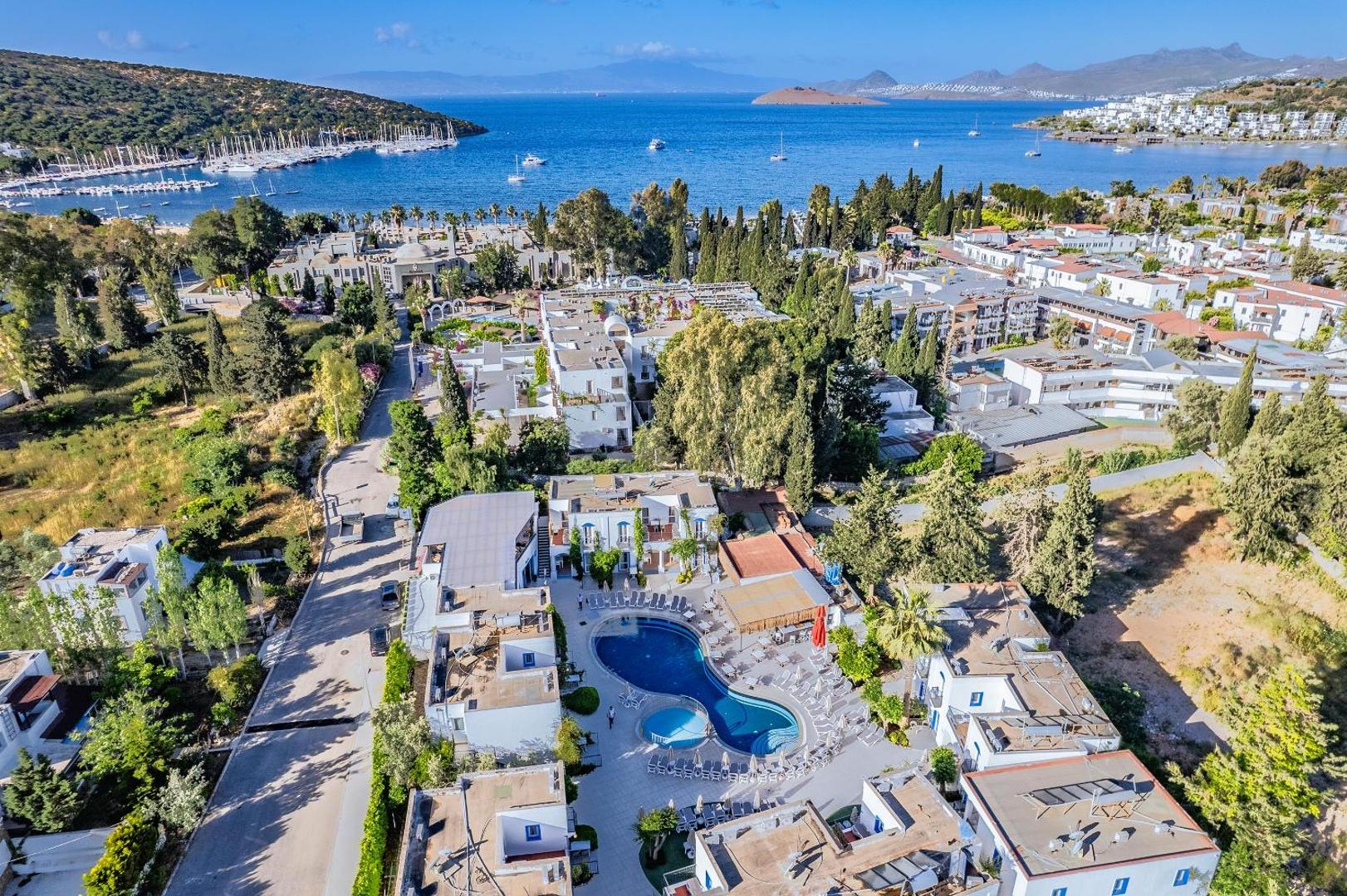Paloma Marina Suites panorāmas skats no augšas uz baseinu, viesnīcas korpusiem un jahtu piestātni Kušadasi līča piekrastē