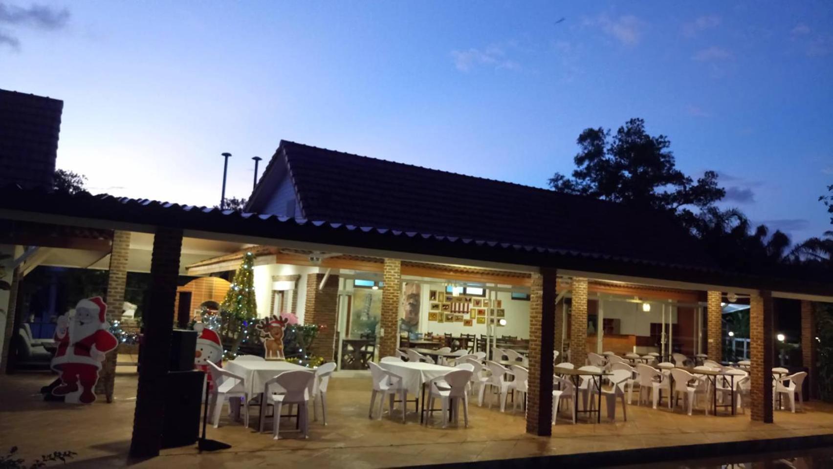 Armonia Holiday Village & Spa restorāna āra zona vakarā ar svētku dekorācijām un balti klātiem galdiem zem nojumes
