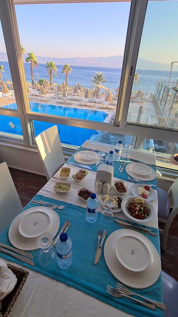 Skats no Armonia Holiday Village & Spa restorāna terases uz āra baseinu un Egejas jūru saulrietā Bodrumas reģionā
