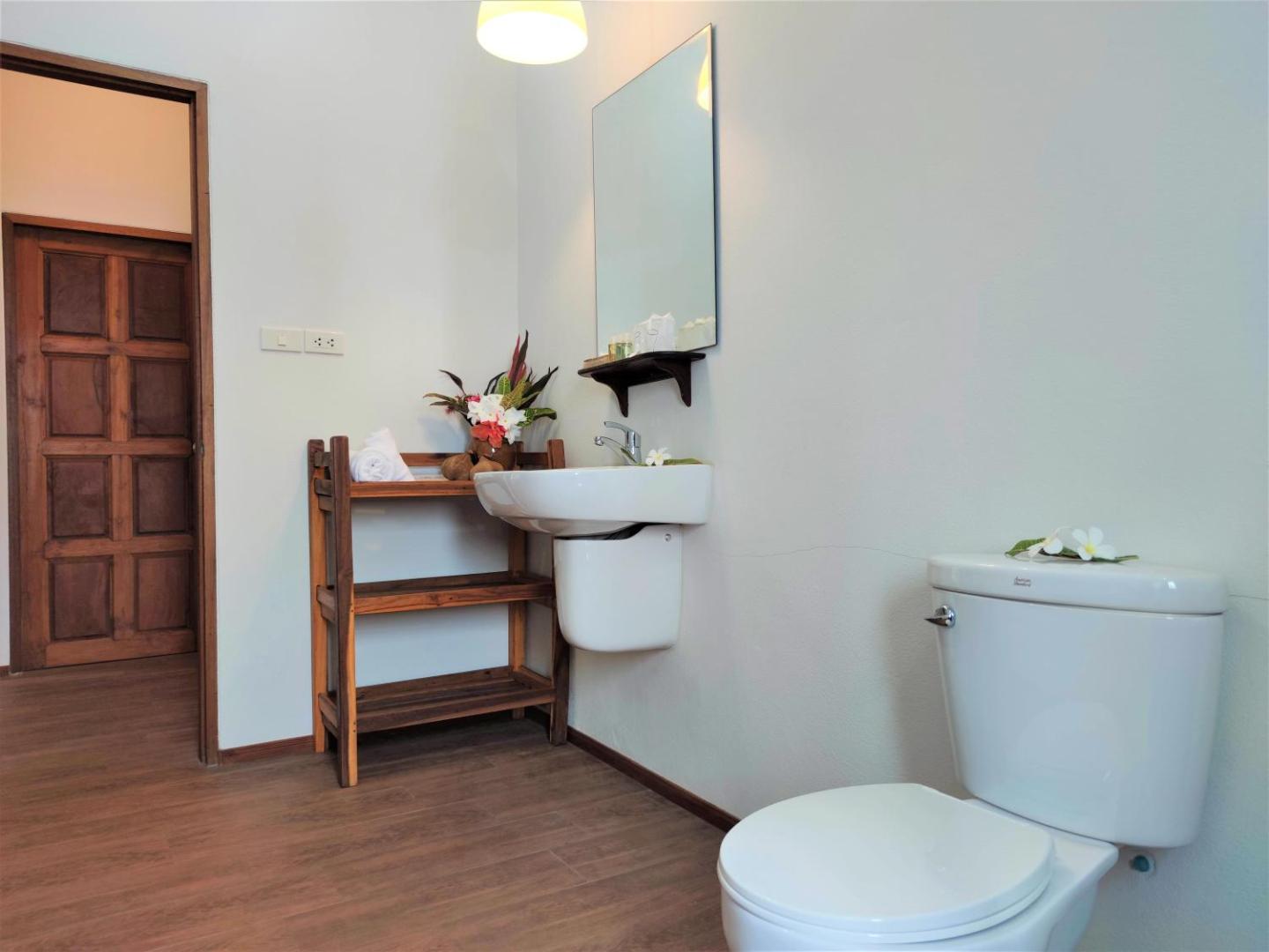 Gaiša Armonia Holiday Village & Spa numura vannas istaba ar koka plauktiem un ziedu dekorācijām mājīgai atmosfērai