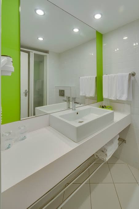 Mūsdienīgs Armonia Holiday Village & Spa viesnīcas numura vannas istabas interjers ar baltu izlietni un zaļiem akcentiem