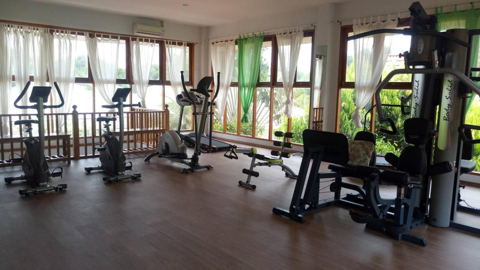 Armonia Holiday Village & Spa fitnesa centrs ar trenažieriem, velotrenažieriem un skrejceliņu gaišā telpā ar lieliem logiem Bodrumā