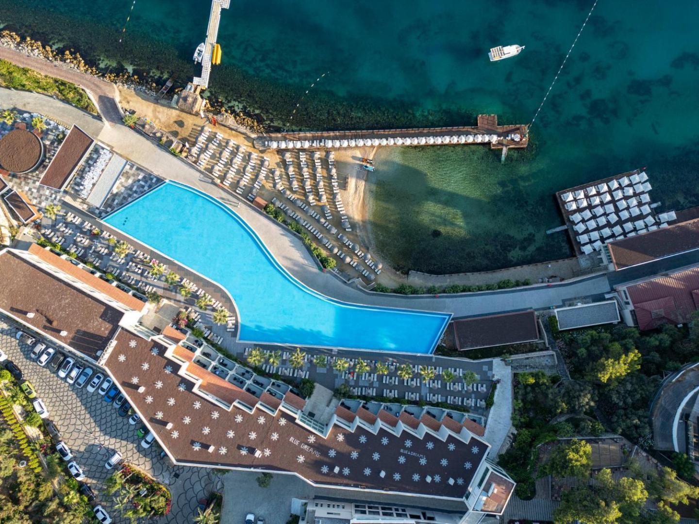 Blue Dreams Resort & Spa aerofoto uzņēmums no augšas — liels āra baseins, privātā pludmale ar piestātni un viesnīcas korpuss Bodrumā.