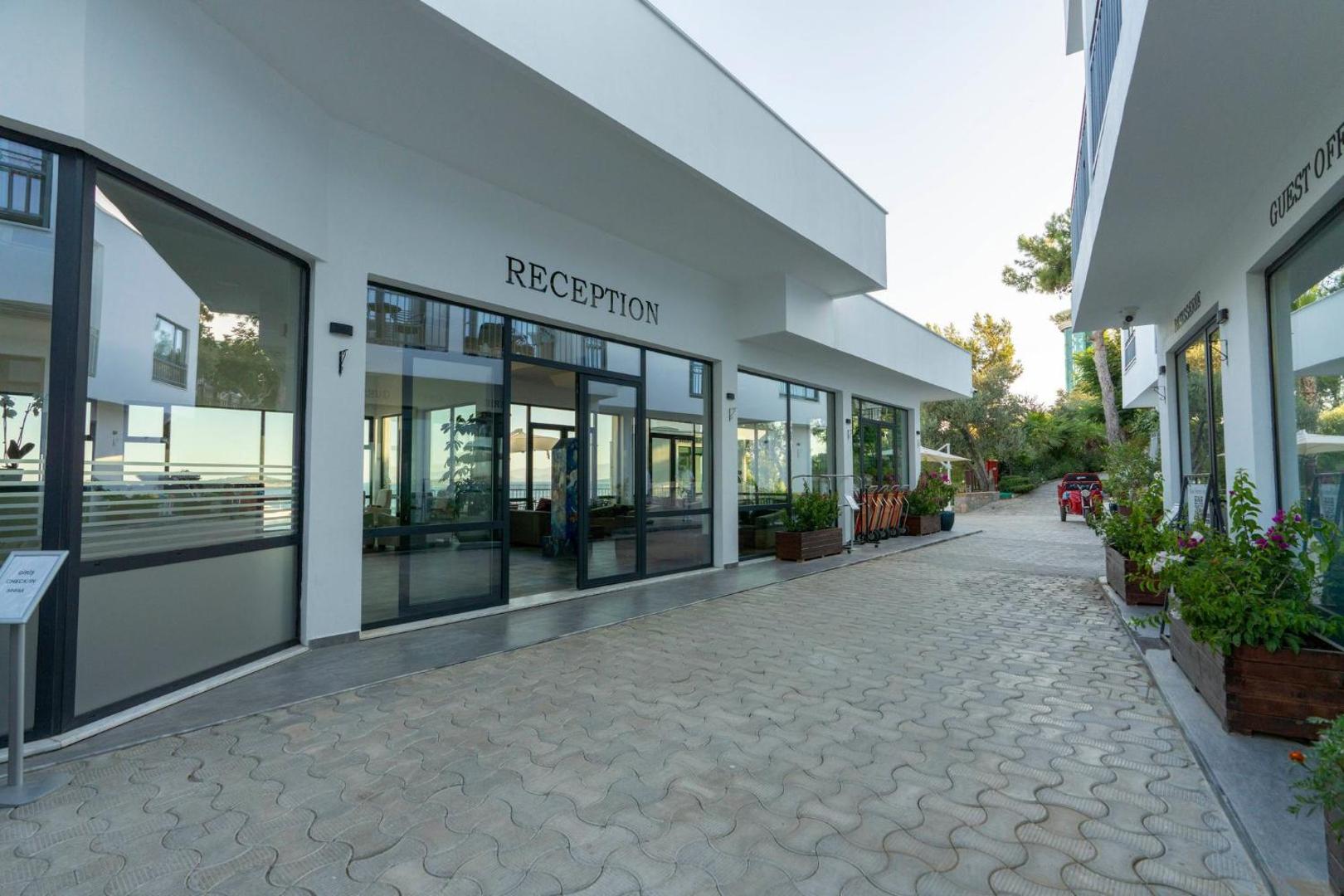 Blue Dreams Resort & Spa modernā recepcijas ēka ar stikla fasādi un bruģētu piebraucamo ceļu Bodrumā