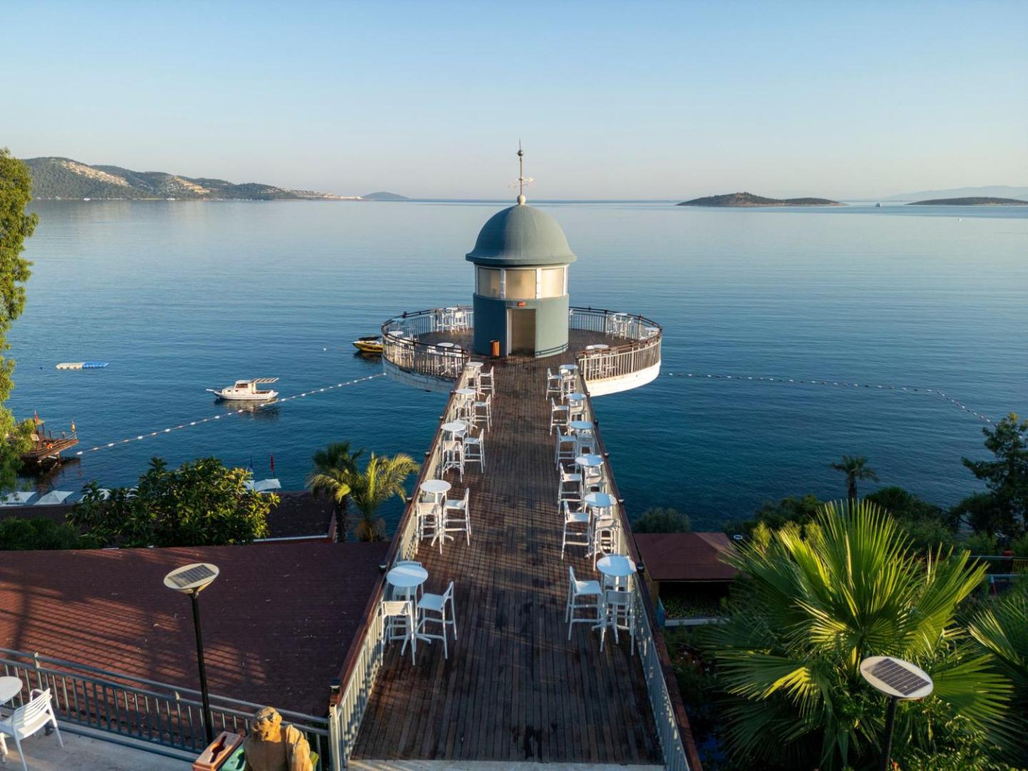 Blue Dreams Resort & Spa koka mols ar galdiņiem un bāru virs Egejas jūras dzidrajiem ūdeņiem Bodrumas reģionā