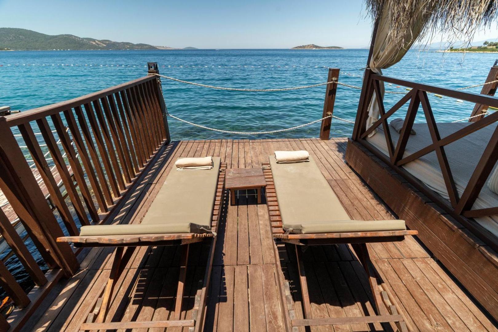 Koka terase ar sauļošanās krēsliem Blue Dreams Resort viesnīcā — tieša piekļuve Egejas jūrai un skats uz salām