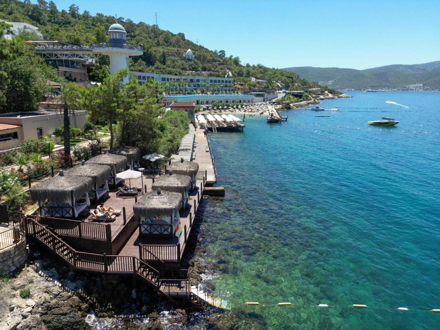 Aerofoto skats uz Blue Dreams Resort piekrasti ar koka terasēm, bungalo tipa atpūtas zonām un tirkīzzilu jūras ūdeni