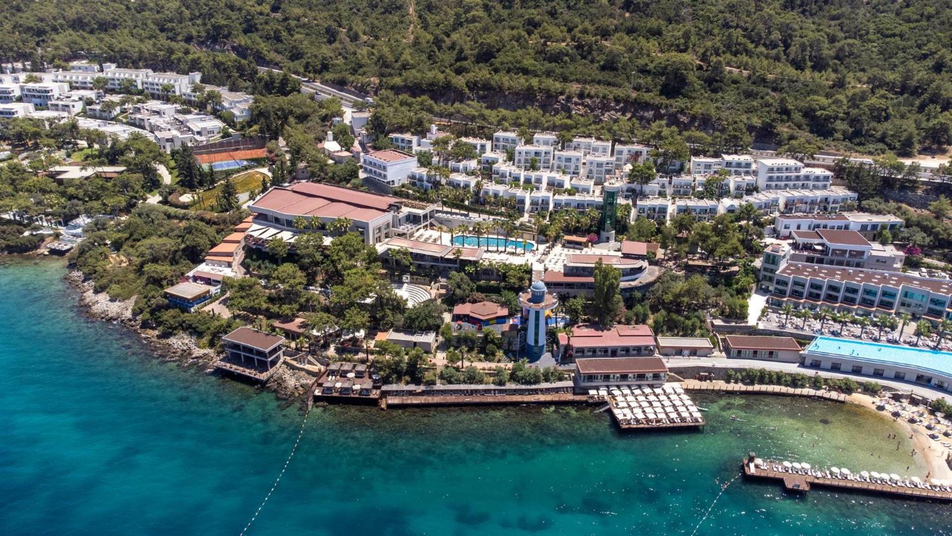 Blue Dreams Resort & Spa aerofoto uzņemums ar viesnīcas ēkām, tenisa kortiem un zaļo teritoriju Bodrumas piekrastē