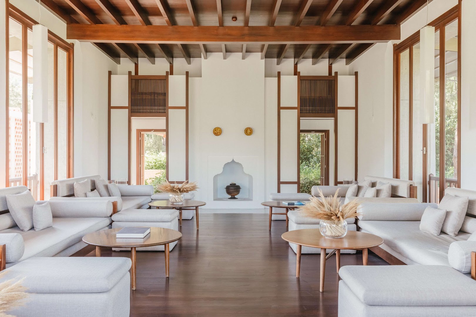 Amanruya Resort Hotel gaiša lobby zona ar minimālistiskiem dīvāniem, koka griestu sijām un lieliem logiem uz dārzu Bodrumā, Turcijā.