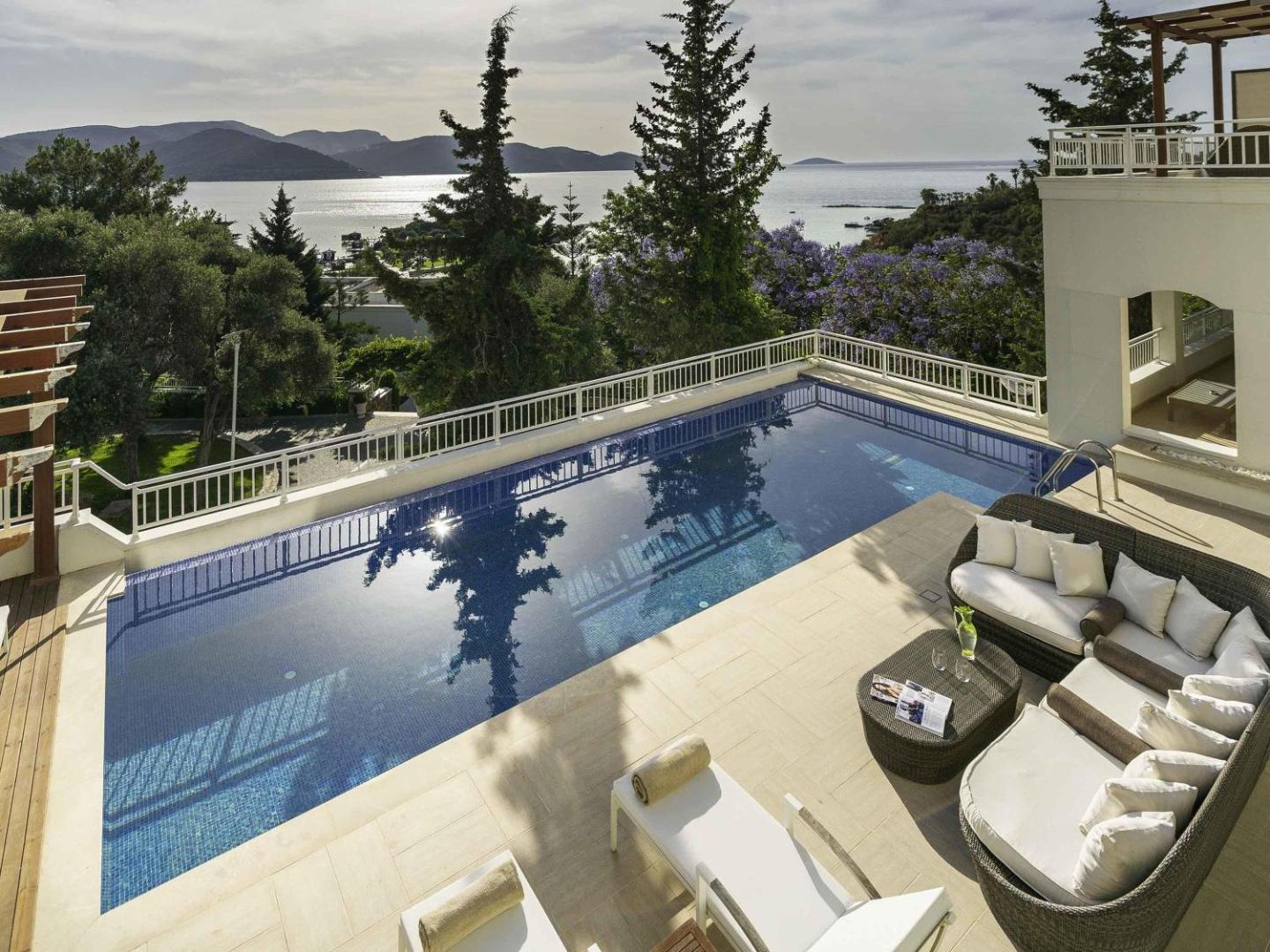 Rixos Premium Bodrum villas privātais baseins ar atpūtas zonu, mīkstajiem dīvāniem un skatu uz Egejas jūras piekrasti un salām