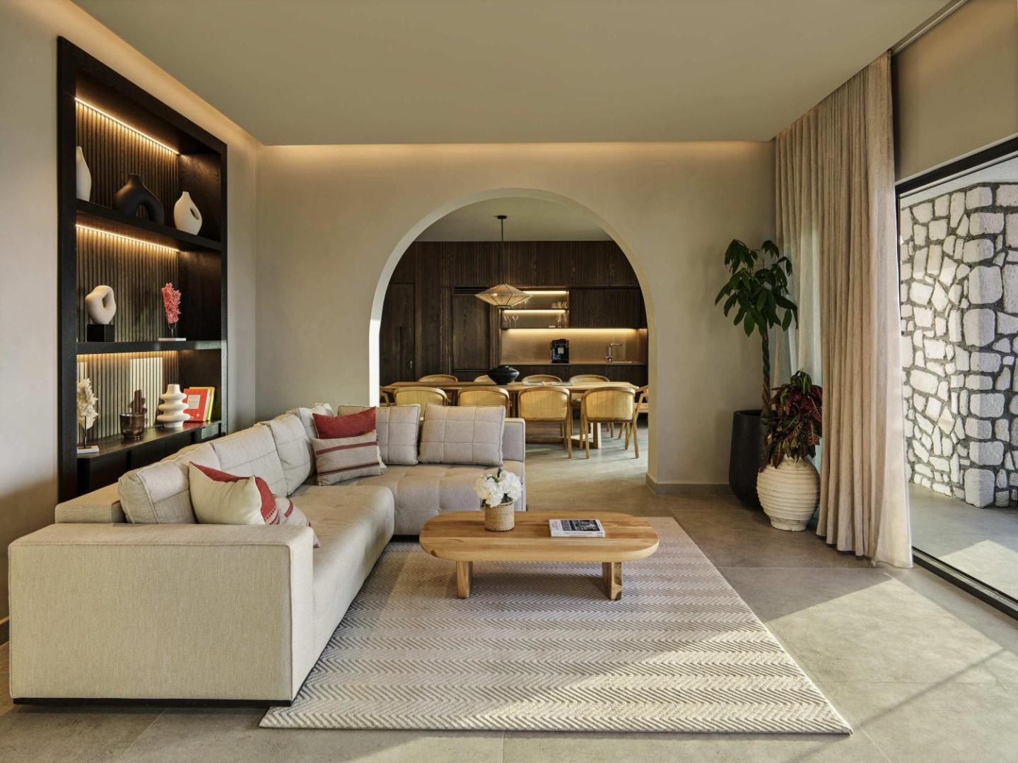 Rixos Premium Bodrum luksusa numura viesistaba ar stūra dīvānu, ēdamzonu un arkas elementu interjerā