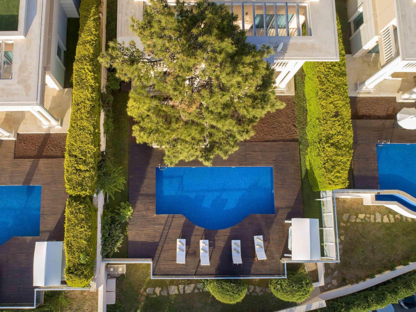 Rixos Premium Bodrum villas teritorijas skats no augšas ar privāto baseinu, koka klāju un zaļiem dzīvžogiem privātumam