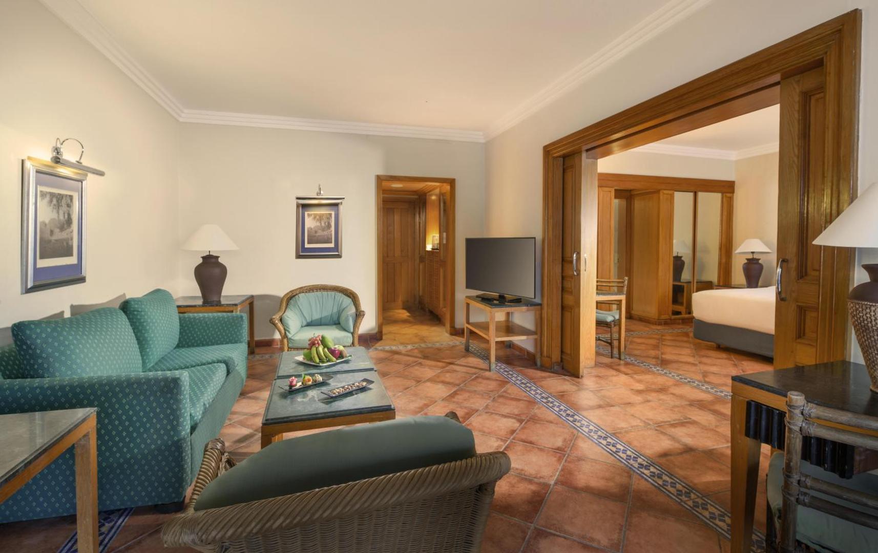 Jaz Sharm Dreams Resort viesnīcas numura viesistabas zona ar dīvānu, atpūtas krēsliem un televizoru Šarm eš Šeihā