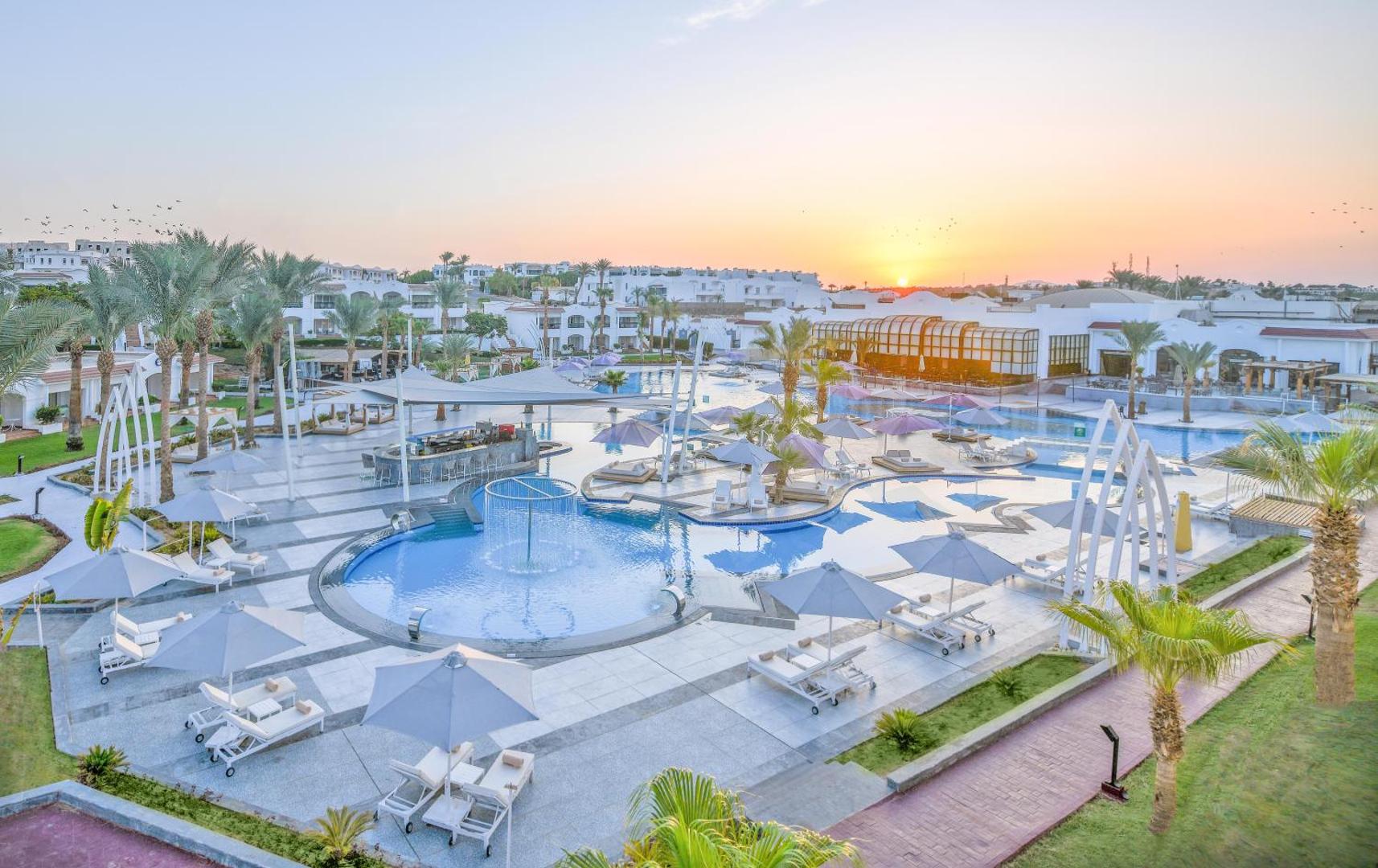 Jaz Sharm Dreams Resort āra baseinu komplekss saulrietā ar bāru un atpūtas krēsliem Šarm eš Šeihā, Ēģiptē
