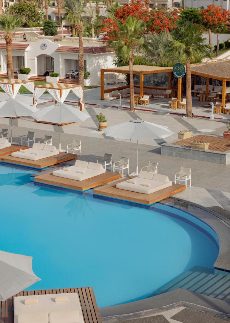 Jaz Sharm Dreams Resort āra baseins Šarm eš Šeihā ar peldošām sauļošanās platformām, saulessargiem un atpūtas zonu palmu ieskautā teritorijā