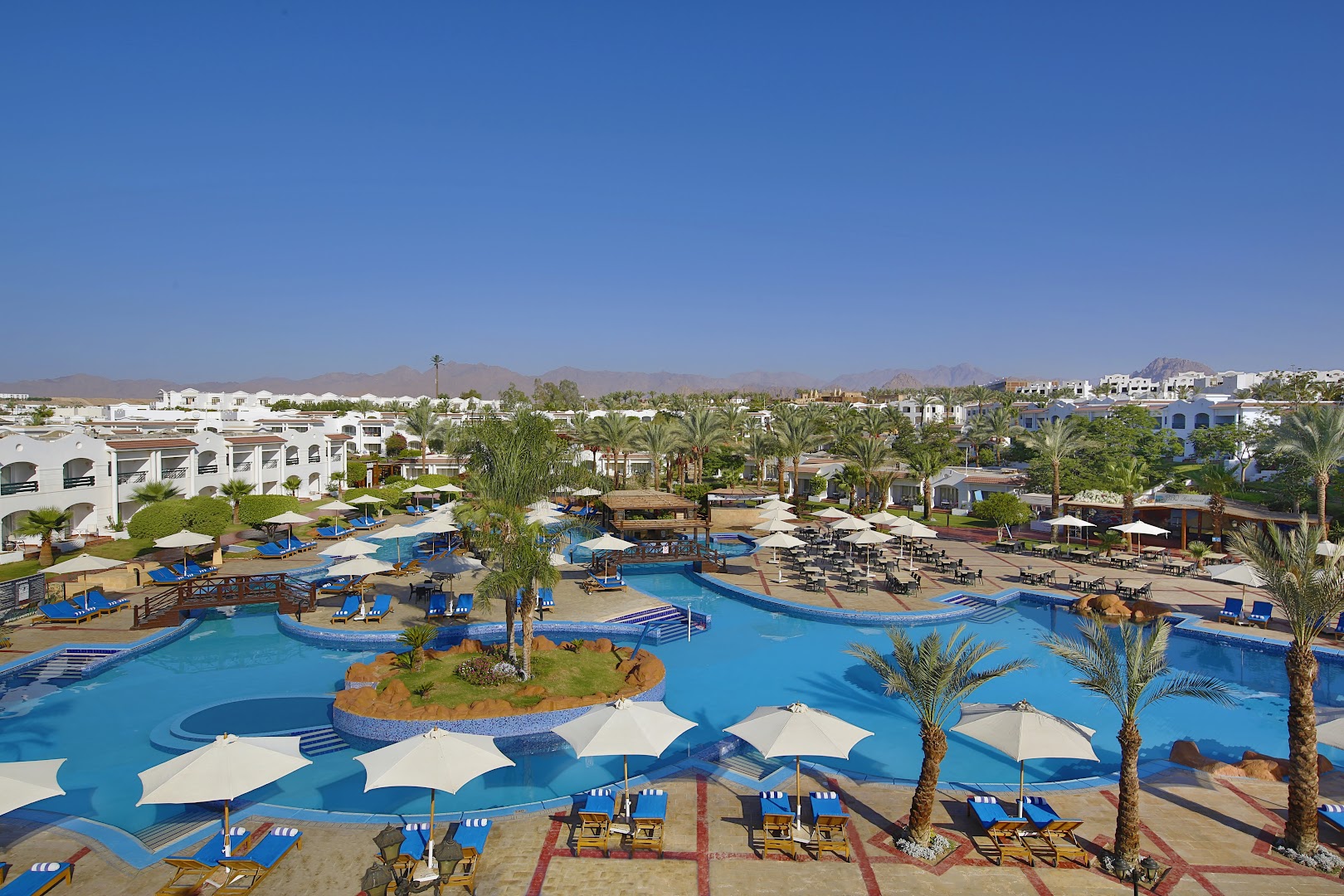 Jaz Sharm Dreams Resort teritorijas skats ar vairākiem baseiniem, tiltiņiem un palmām Šarm eš Šeihā