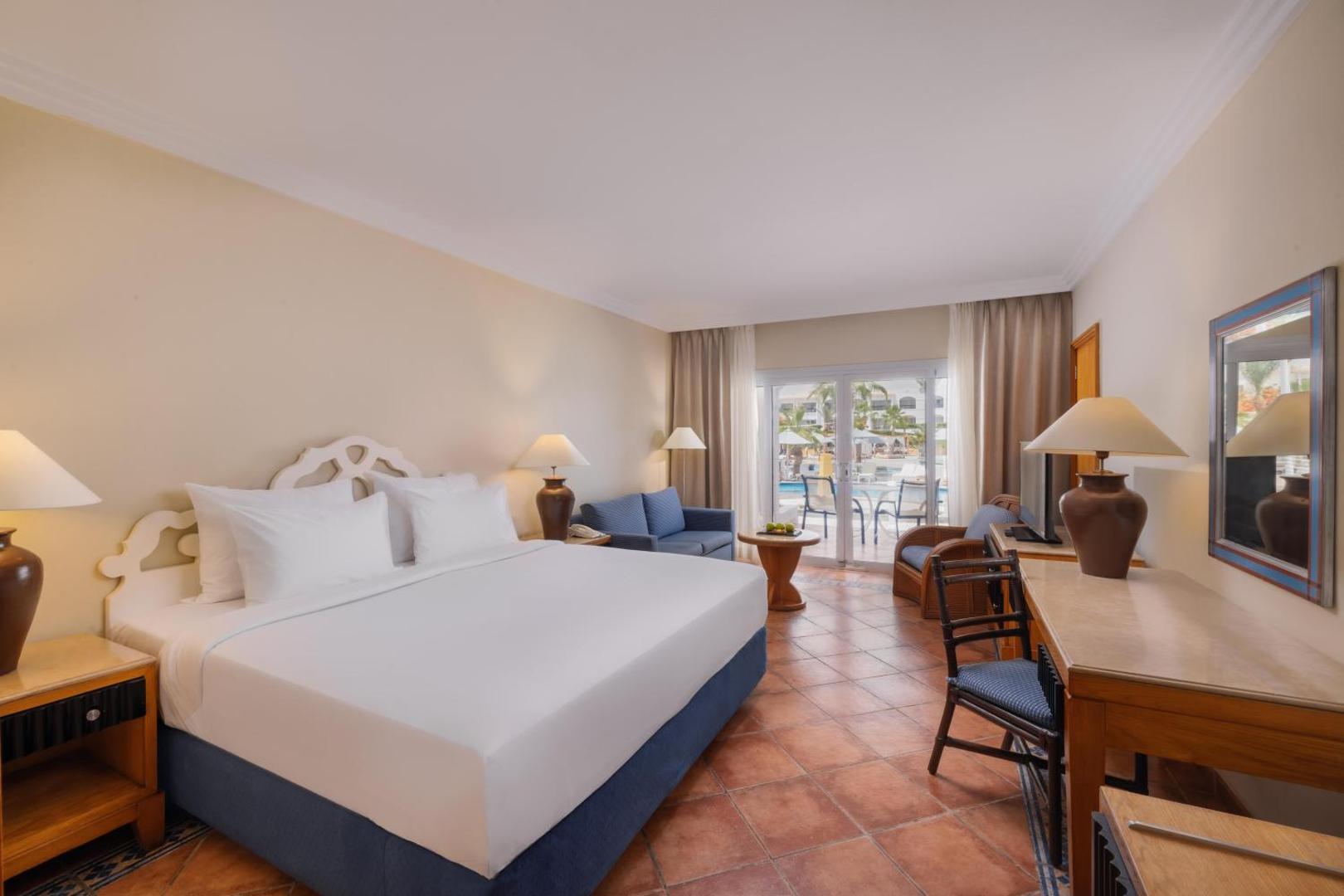 Jaz Sharm Dreams Resort numurs ar lielu divguļamo gultu, atpūtas zonu un terasi, no kuras paveras skats uz baseinu