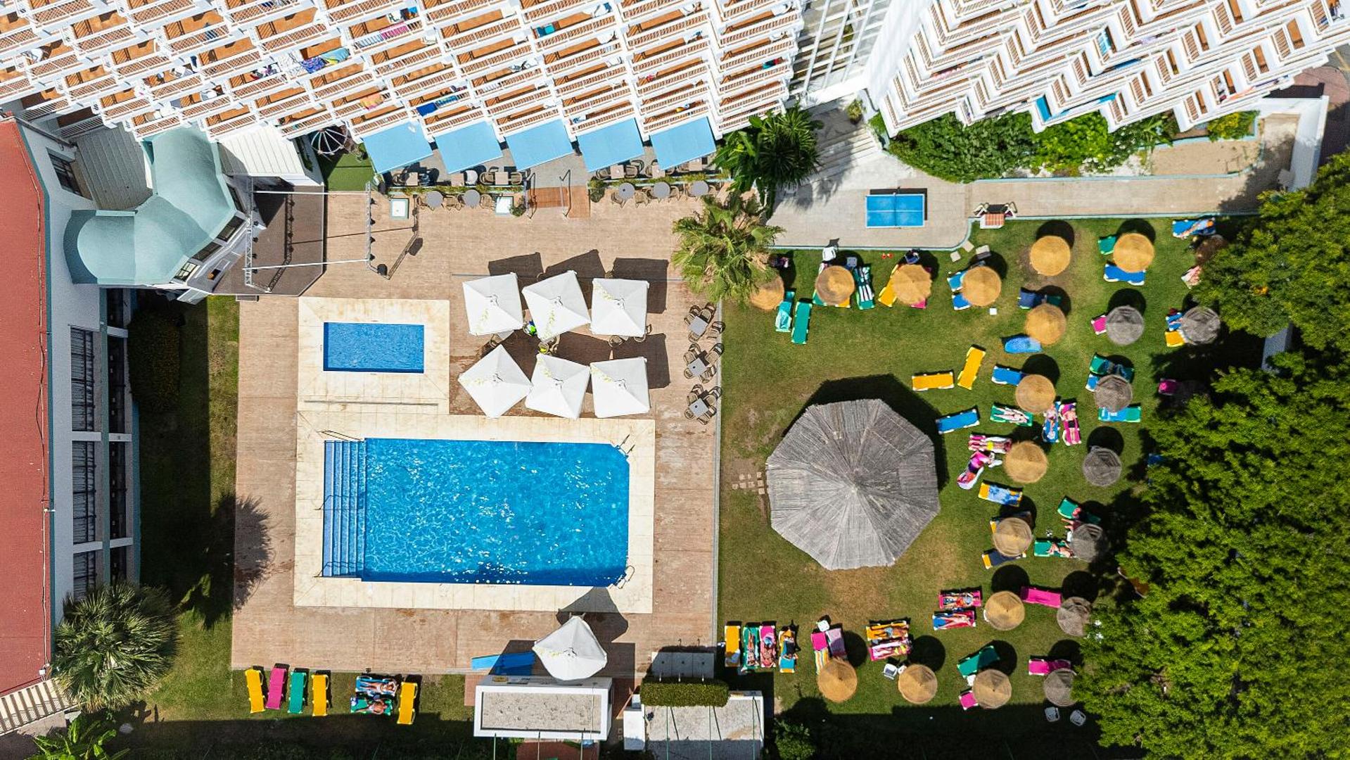 Aerofoto skats uz MedPlaya Hotel Alba Beach baseinu, dārzu ar saulessargiem un atpūtas krēsliem zaļajā zonā pie viesnīcas korpusa