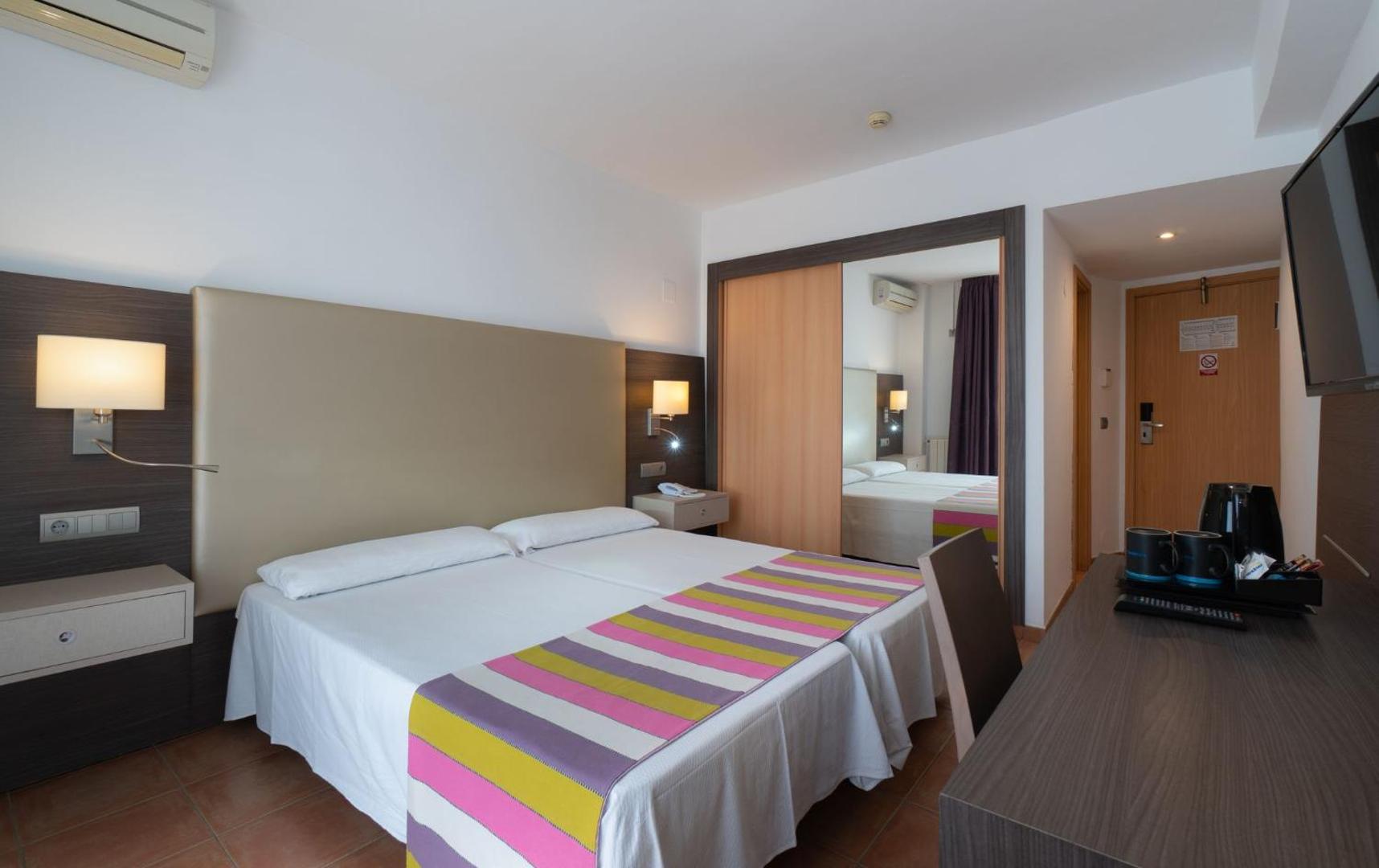 Mūsdienīgs MedPlaya Hotel Alba Beach numurs ar lielu spoguli, darba galdu un krāsainu gultas pārklāju