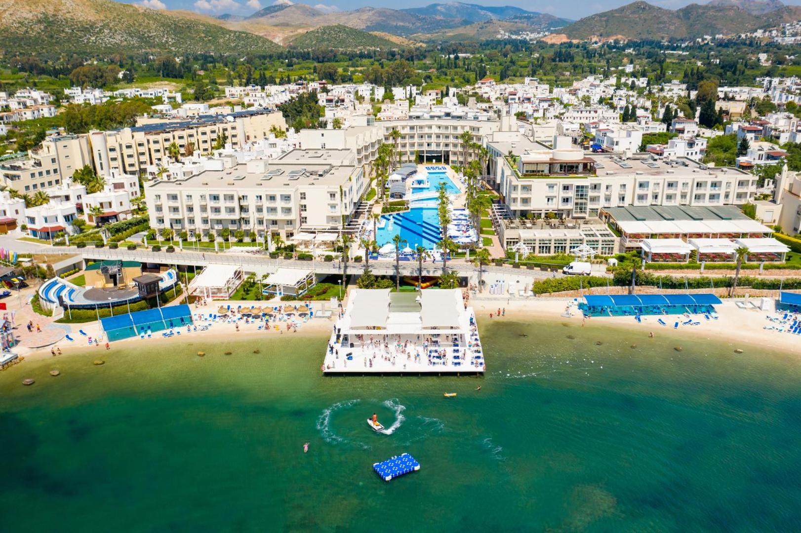 La Blanche Resort & Spa skats uz centrālo baseinu zonu un balto koka platformu jūrā sauļošanās un atpūtas brīžiem
