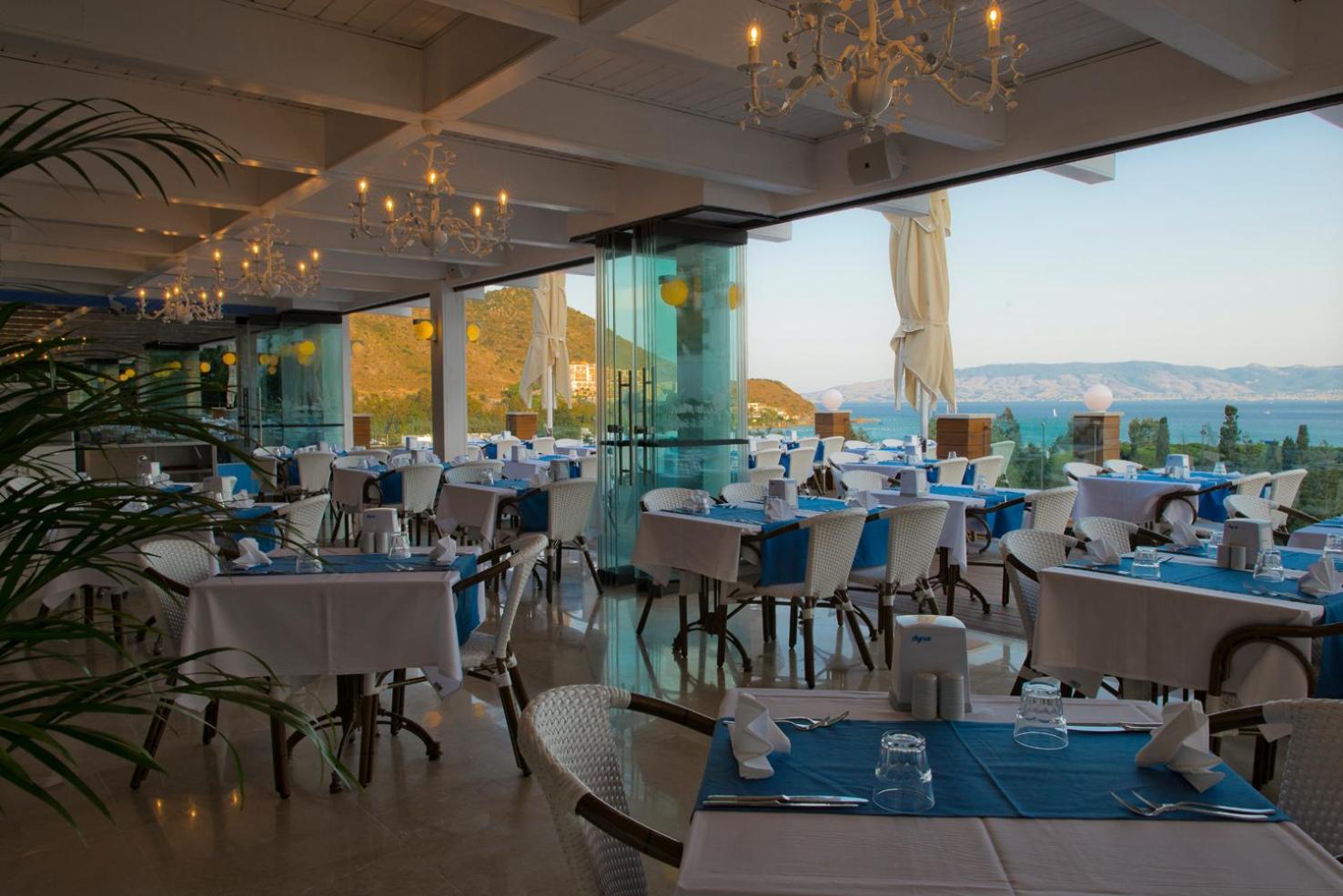 Sentido Bellazure iekštelpu restorāns ar elegantiem zili baltiem galdiem un lieliem logiem, no kuriem paveras skats uz jūru
