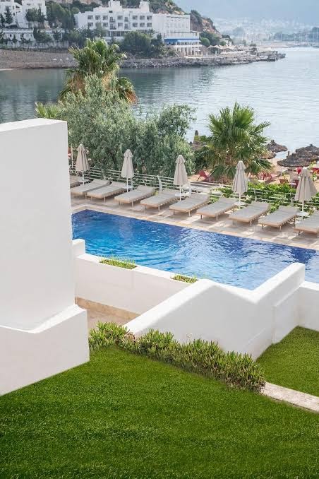 Panorāmas skats uz Prive Hotel Bodrum baseinu, sauļošanās zonu un blakus esošo līci ar jahtām tālumā