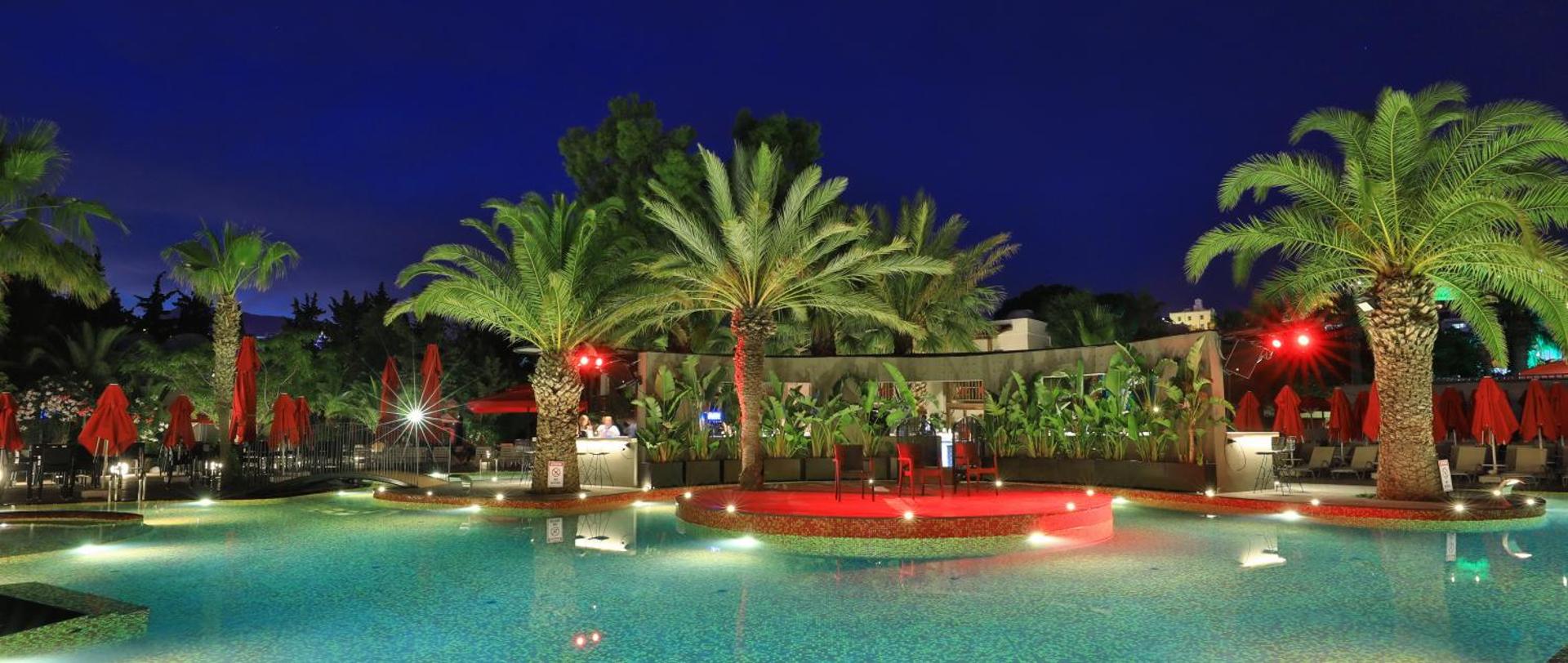 Otium Senses Very Chic āra baseins vakarā ar izgaismotām palmām un atpūtas zonu Bodrumā — romantiska atmosfēra pie ūdens
