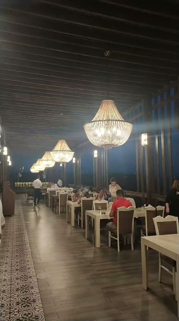Laur Hotels Experience & Elegance vakariņu zona uz terases ar greznām lustrām un servētiem galdiem viesiem vakara stundās