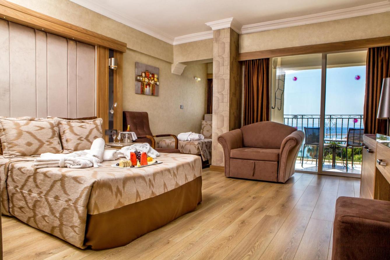 LAUR HOTELS Experience & Elegance gaišs numurs ar skatu uz jūru, balkonu, atpūtas krēslu un augļu plati uz gultas