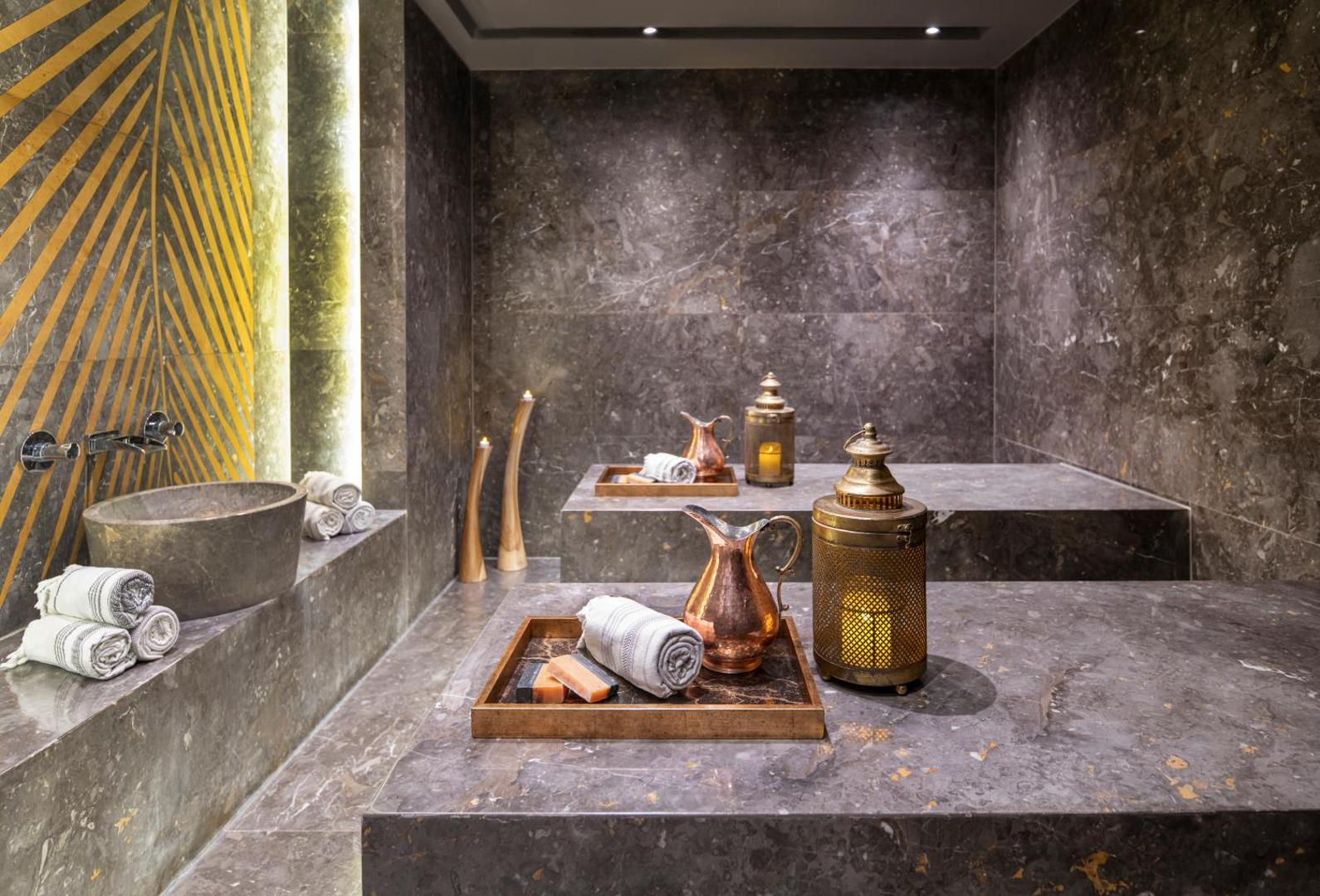 Lujo Hotel Bodrum spa centra hamama zona ar marmora apdari, akmens izlietni, svecēm un tradicionāliem vara traukiem relaksējošai atmosfērai