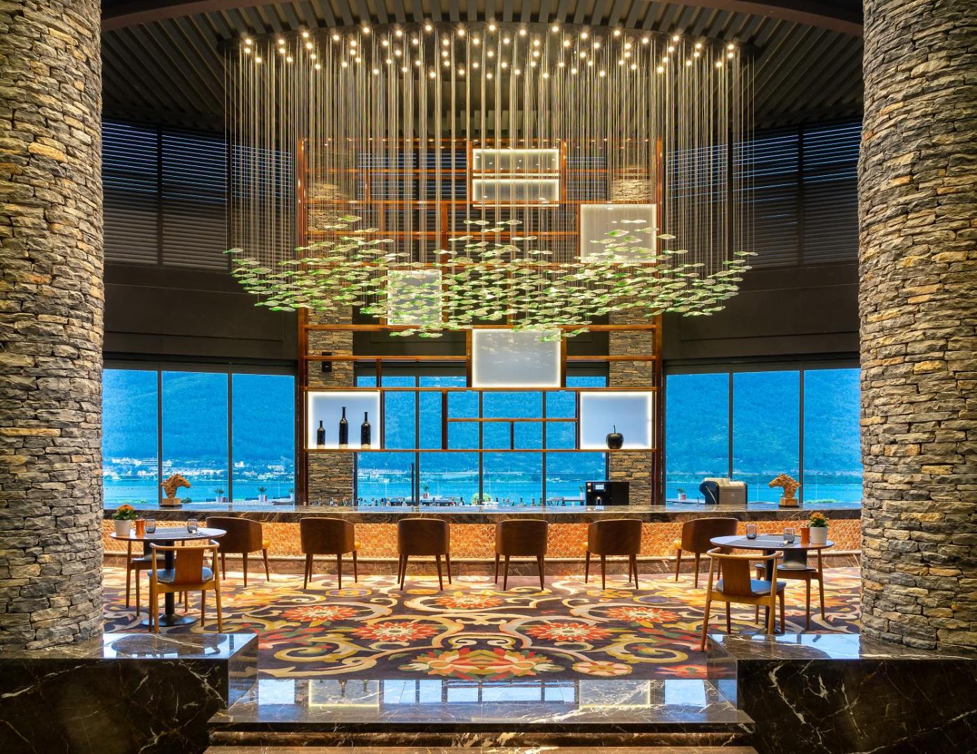 Lujo Hotel Bodrum modernais bārs ar iespaidīgu dizaina lustru, akmens kolonnām un panorāmas skatu uz Egejas jūru un kalniem