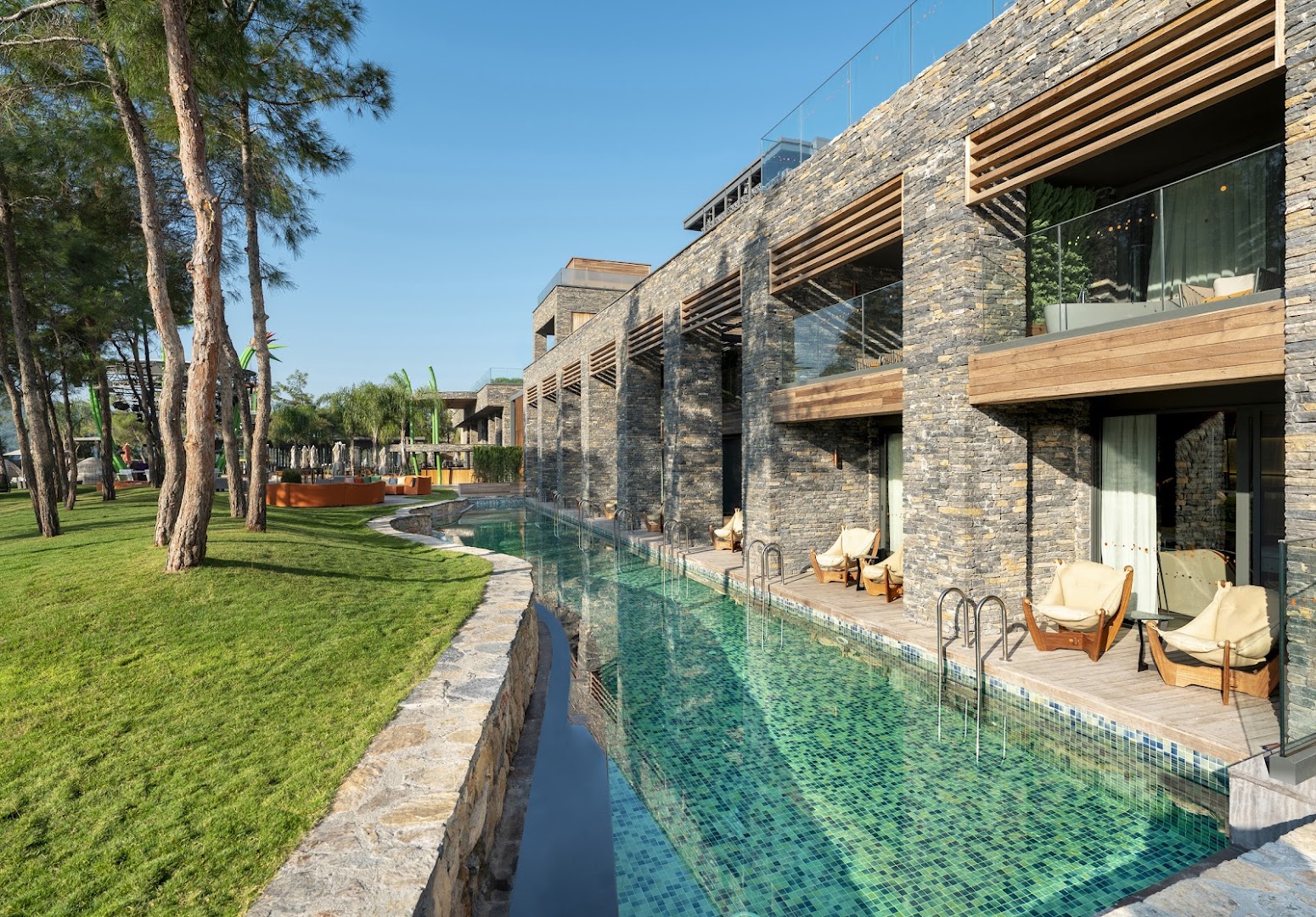 Lujo Hotel Bodrum swim-up numuri ar tiešu piekļuvi baseinam, akmens sienām un zaļu mauriņu priežu ielokā piekrastē