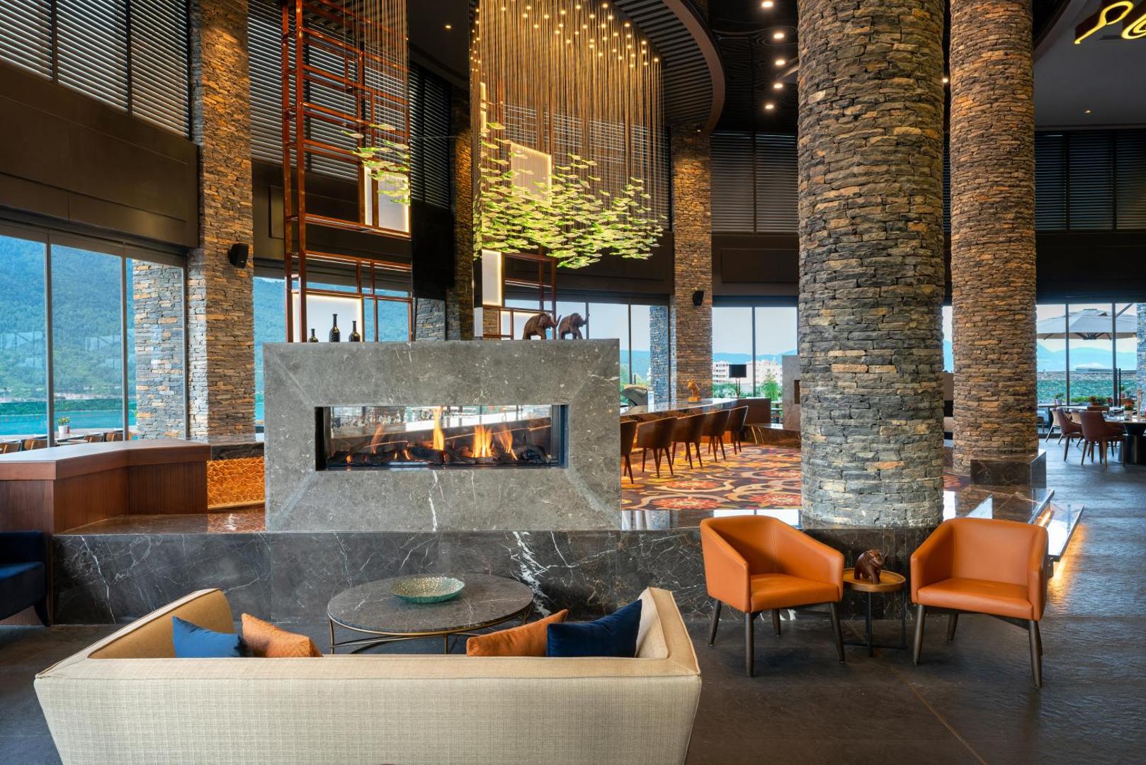 Lujo Hotel Bodrum lobby bārs ar modernu kamīnu, akmens kolonnām un dizaina mēbelēm elegantā interjerā.