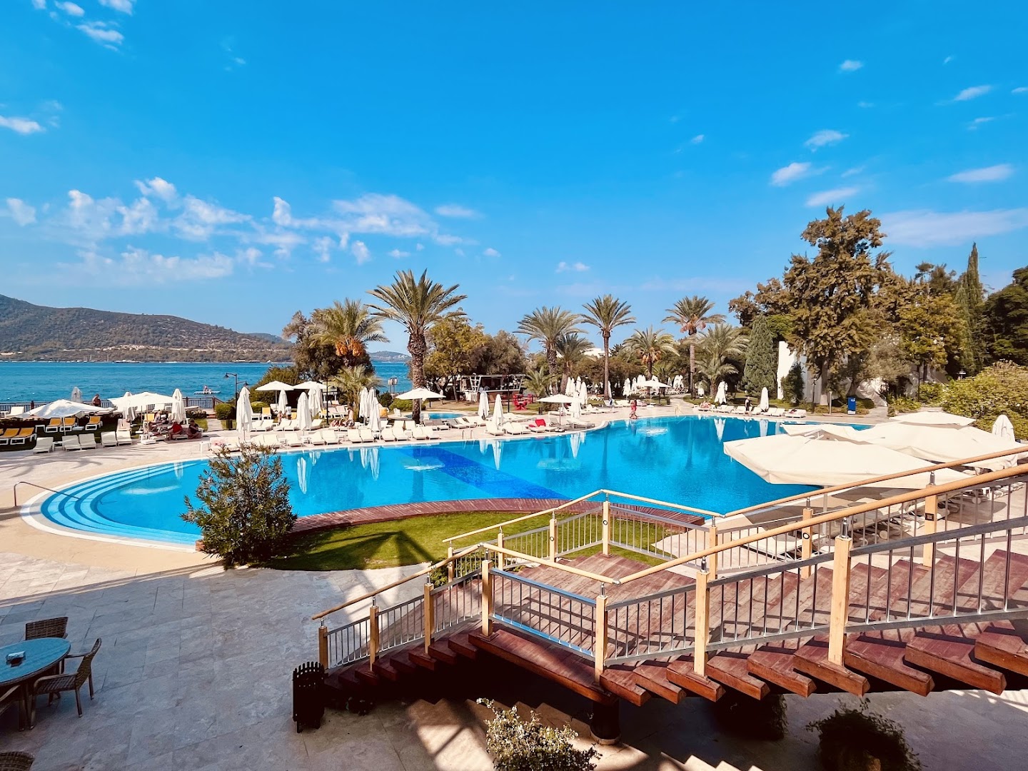 Skats no terases uz DoubleTree by Hilton Bodrum Isil Club Resort baseinu un Egejas jūru saulainā dienā