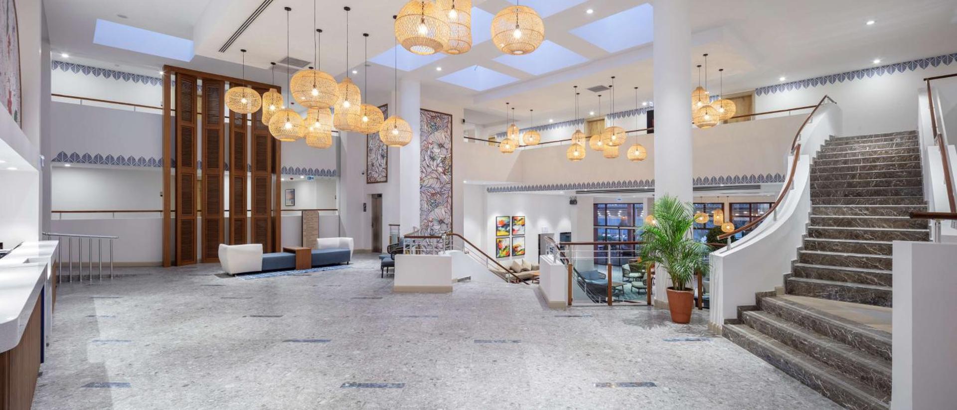 DoubleTree by Hilton Bodrum Isil Club Resort gaišais vestibils ar marmora grīdu, augstiem griestiem un dekoratīvām pītajām lampām Turcijā