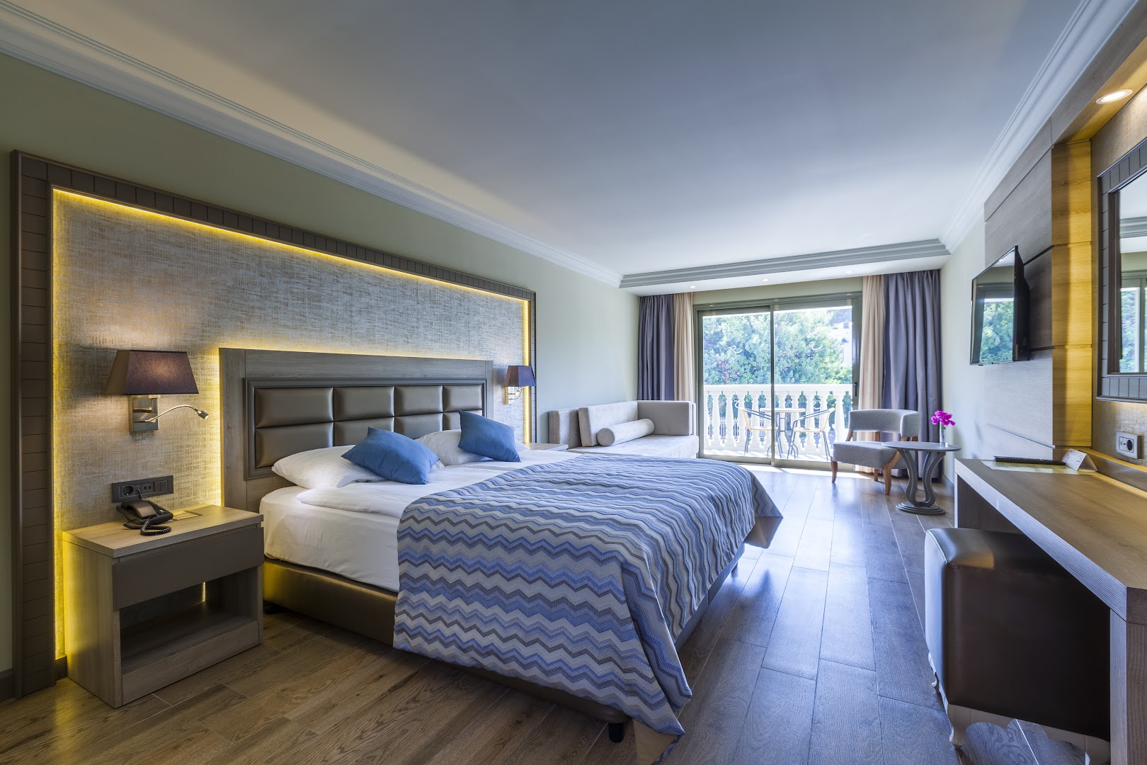 Gaišs Samara Hotel Bodrum viesnīcas numurs ar divguļamo gultu, koka grīdu un balkonu, no kura paveras skats uz dārzu