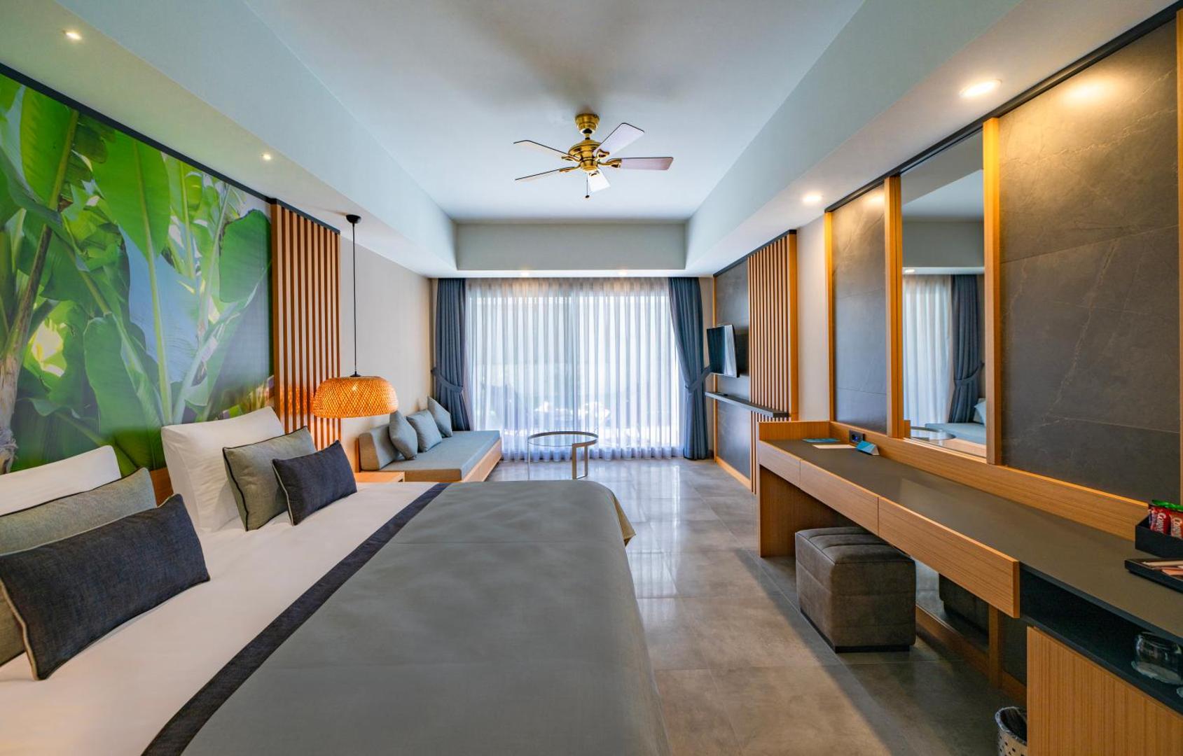 Moderns Samara Hotel Bodrum numurs ar tropisku sienas dekoru, lielu spoguli un plašu logu, kas nodrošina dabisko gaismu