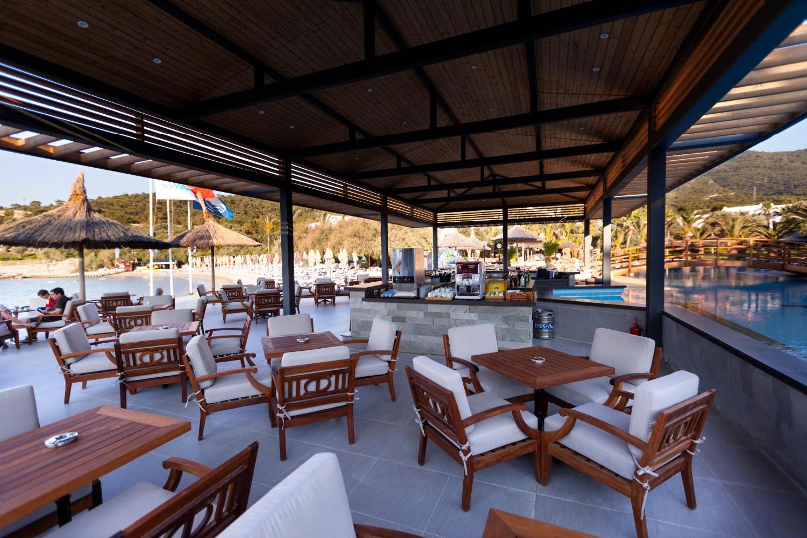 Samara Hotel Bodrum āra bārs un atpūtas zona ar koka mēbelēm pie baseina un pludmales Bodrumas reģionā, Turcijā