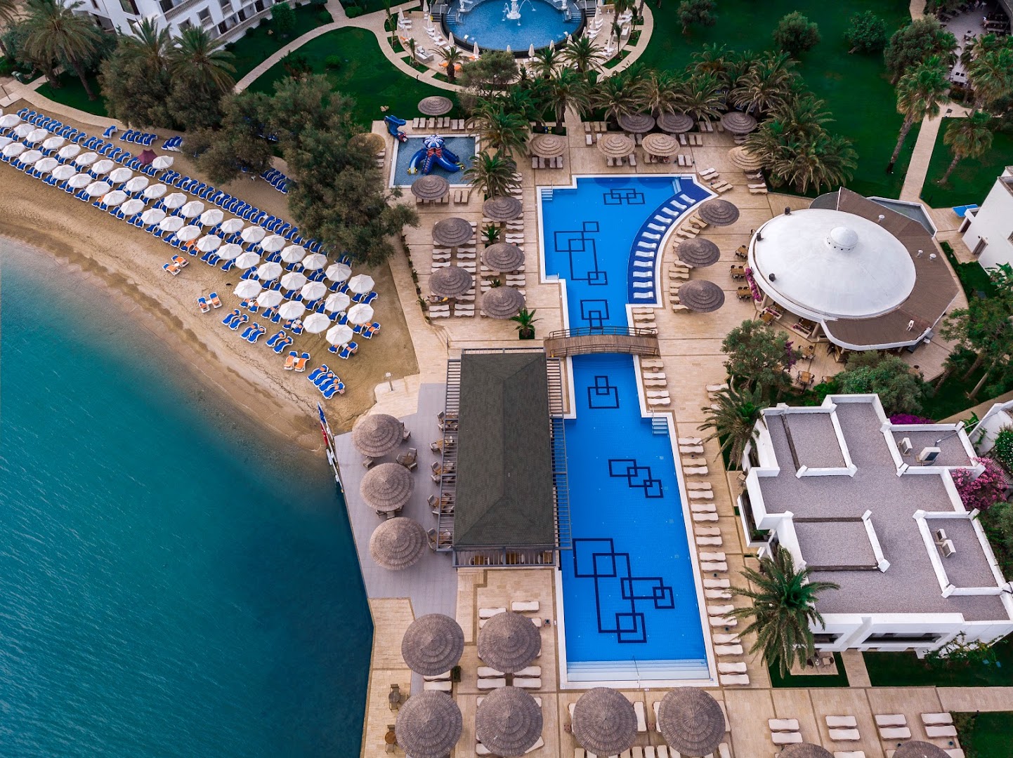 Samara Hotel Bodrum teritorijas skats no putna lidojuma — privātā pludmale, baseini, dārzs un viesnīcas ēkas Bodrumā
