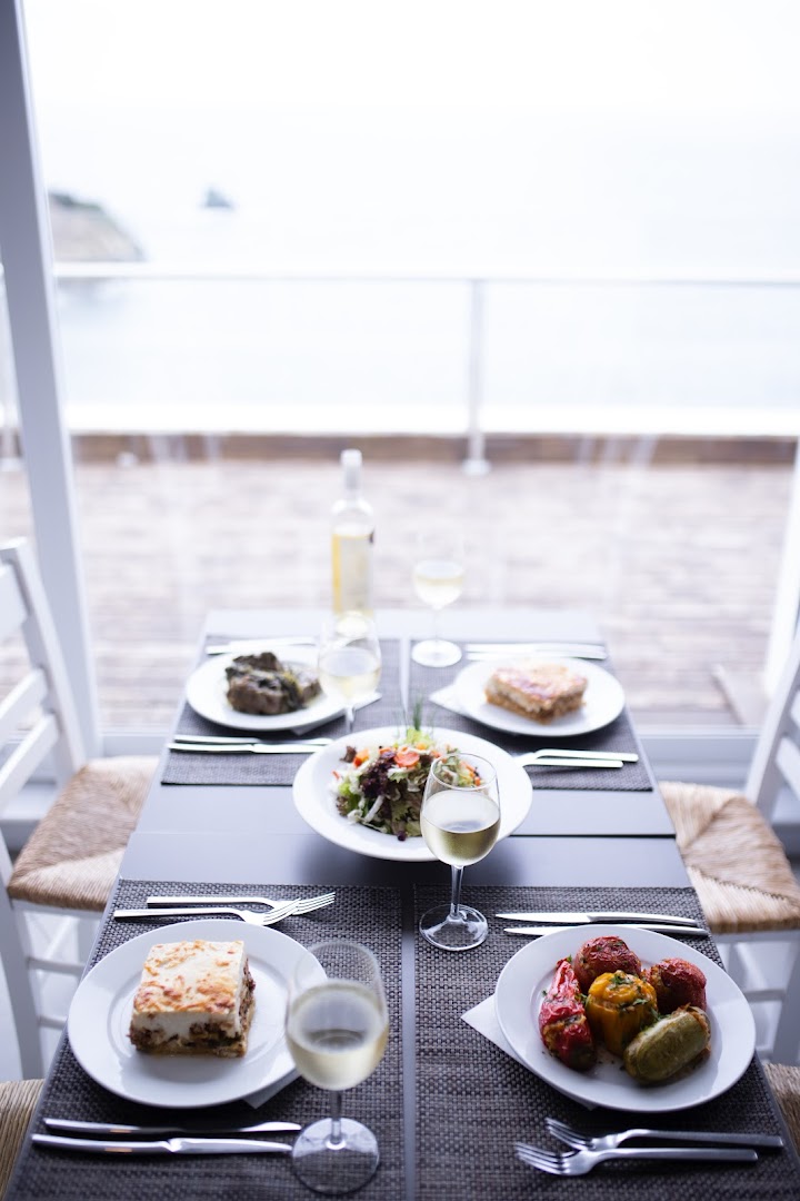 Tradicionālie grieķu ēdieni un vīns uz klāta galda Peninsula Resort & Spa restorānā ar skatu uz piekrasti