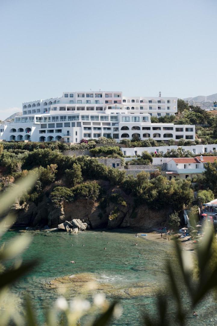 Skats caur zaļumiem uz Peninsula Resort & Spa galveno ēku un nelielu pludmales līci ar dzidru ūdeni