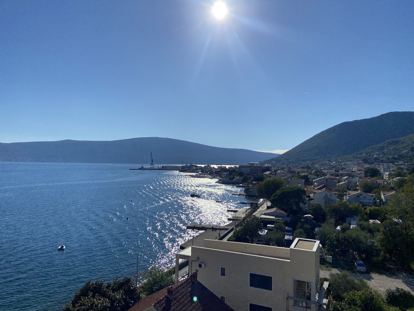 Skats no Carine Hotel Park augšējiem stāviem uz Adrijas jūras piekrasti un kalniem Melnkalnē saulainā dienā