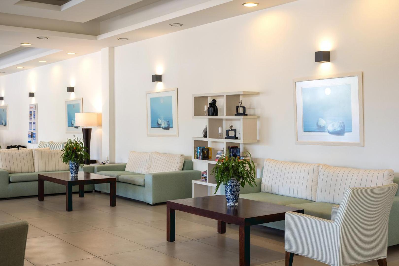 Ariadne Beach viesnīcas lobby atpūtas zona ar gaišiem dīvāniem, kafijas galdiņiem un modernu interjeru Krētas piekrastē