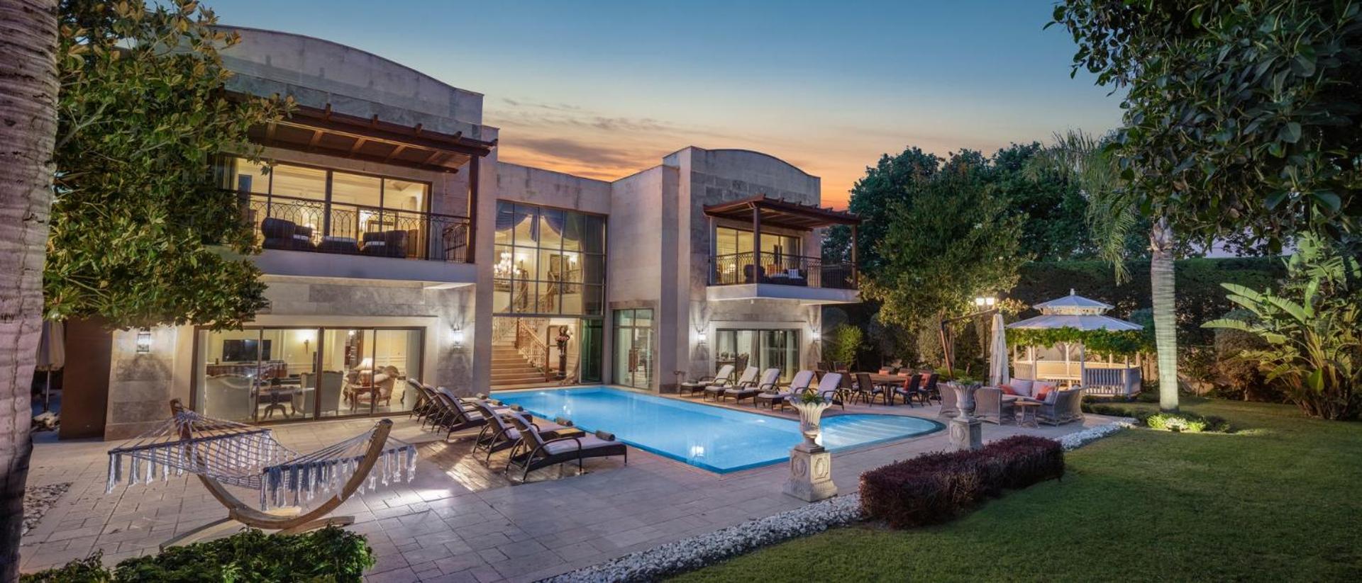 Ela Excellence Resort Belek luksusa villa ar privātu baseinu, sauļošanās krēsliem un dārzu saulrieta laikā Belekas reģionā, Turcijā.