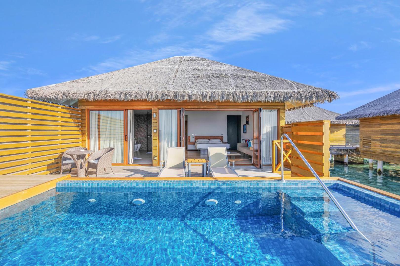 Cocoon Maldives bungalo eksterjers ar privātu baseinu un atvērtām durvīm uz dzīvojamo zonu zem zilām debesīm