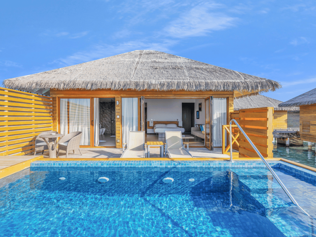 Cocoon Maldives luksusa bungalo terase ar privātu baseinu, sauļošanās krēsliem un skatu uz guļamistabu saulainā dienā
