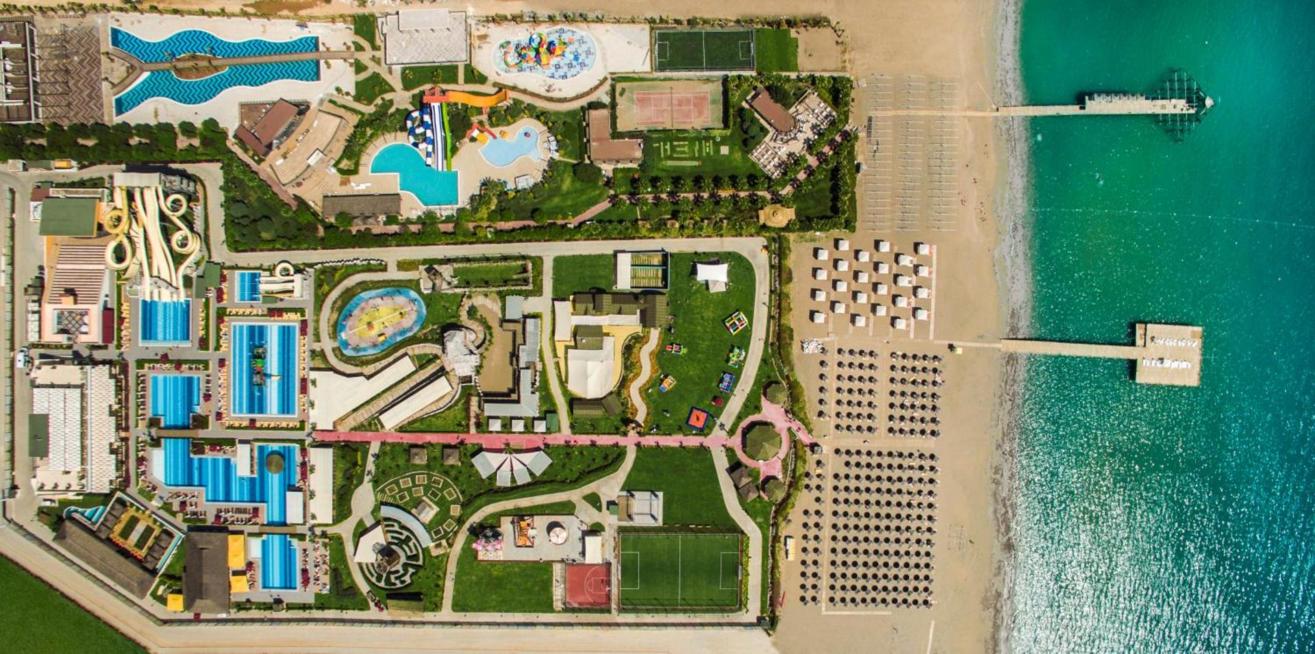 Aska Lara Resort & Spa teritorijas skats no putna lidojuma — akvaparks, sporta laukumi, privātā pludmale un piestātnes Vidusjūras krastā